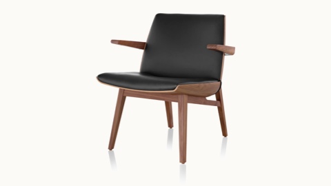 Angled view of a low-back Clamshell Lounge Chair with black leather upholstery and four wood legs.
