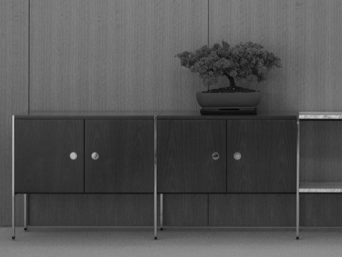 Black-and-white image of an H Frame Storage credenza positioned against a wall, with a small bonsai tree atop one module.