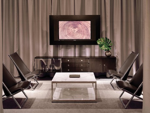 A lounge area featuring an H Frame coffee table with stone surfaces, a coordinating H Frame credenza, and four black leather Scissor Chairs.