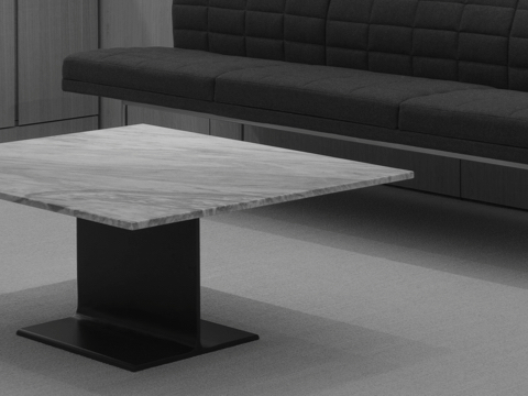 Black-and-white image of an I Beam coffee table with a marble top in an executive lounge.