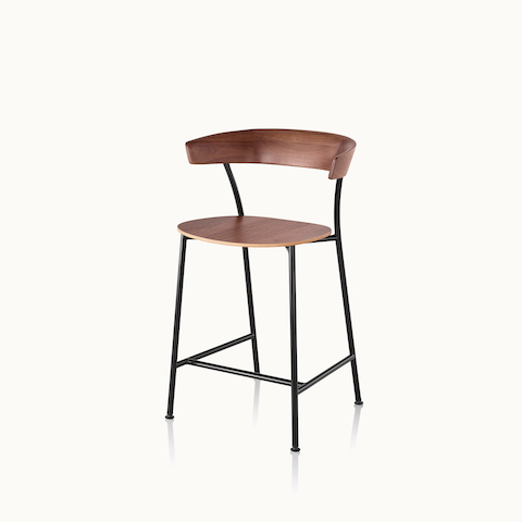 Angled view of a Leeway Stool with a black metal frame and a wood backrest and seat in a medium finish. Select to go to the Leeway Stool product page.