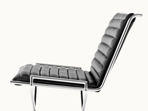 Close-up on the ribbed seat and back of a Sled lounge chair with black leather upholstery, viewed from the side.