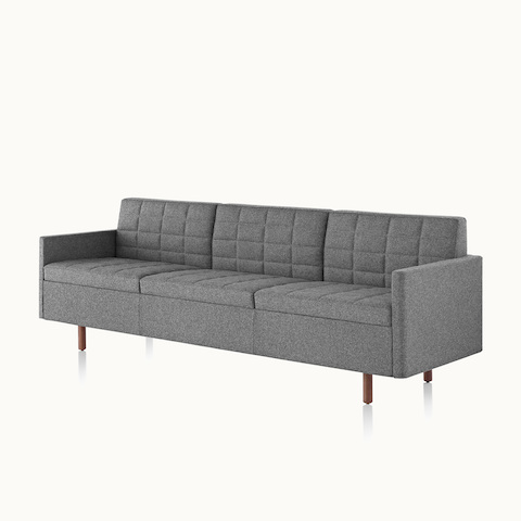 Angled view of a Tuxedo Classic sofa with dark gray quilted upholstery. Select to go to the Tuxedo Classic Lounge Seating product page.