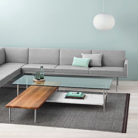 A non-quilted Tuxedo Component sectional upholstered in light gray fabric partially surrounds an L-shaped Layer coffee table.